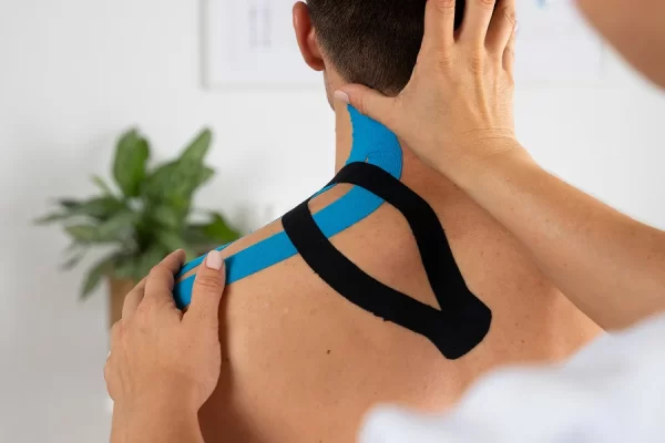 A man receives a back massage while sports taping is applied to his shoulder for support and recovery.